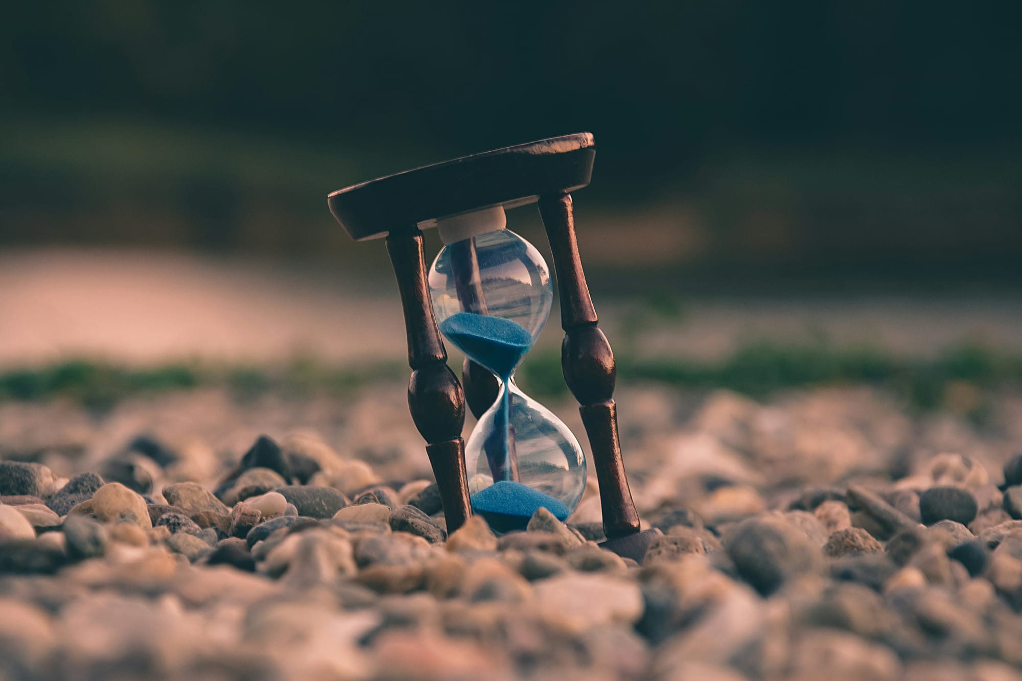 Hourglass with blue sand on rocks